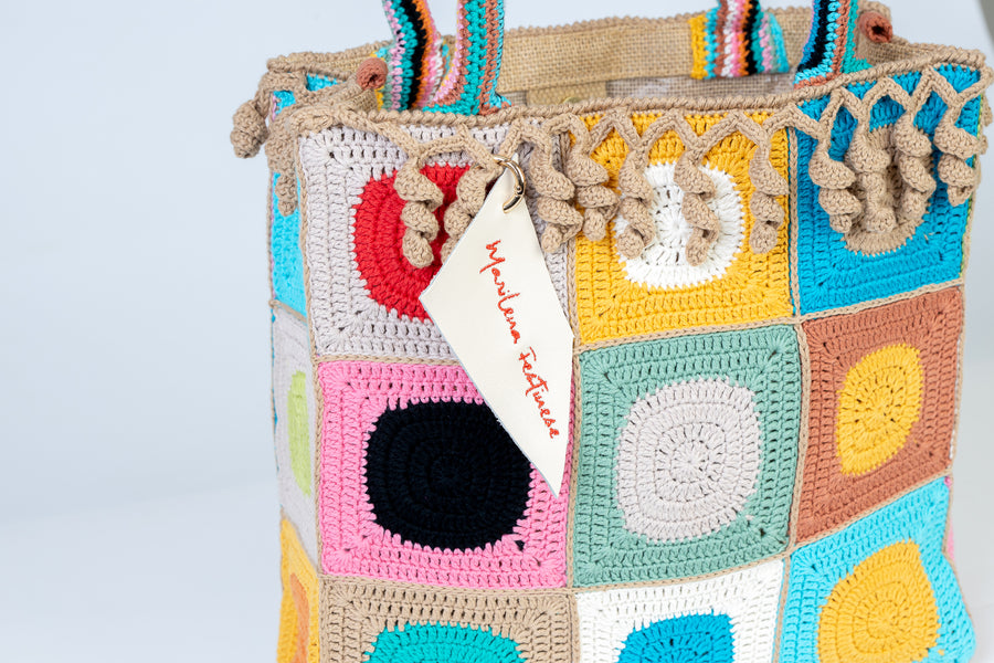 Design patchwork coronato da una splendida e sottile cornice beige, completata da un manico multicolore e dagli “sbaruffi” elicoidali. Tote Bag eccentrica e vivace, realizzata all’uncinetto. La sua tracolla rimovibile permette di portare la borsa a spalla. Di manifattura artigianale, prodotta in Italia.