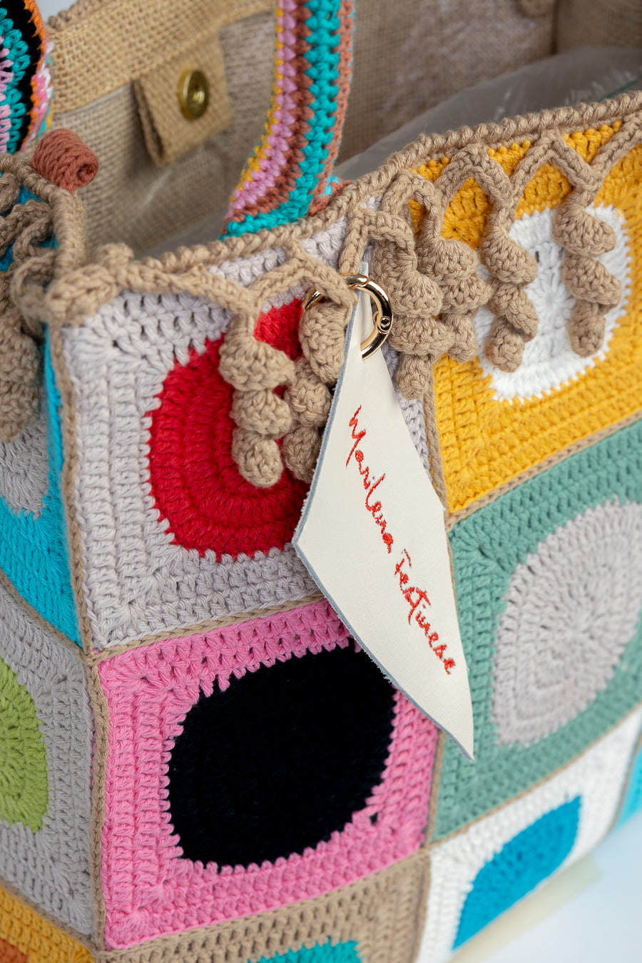 Design patchwork coronato da una splendida e sottile cornice beige, completata da un manico multicolore e dagli “sbaruffi” elicoidali. Tote Bag eccentrica e vivace, realizzata all’uncinetto. La sua tracolla rimovibile permette di portare la borsa a spalla. Di manifattura artigianale, prodotta in Italia.