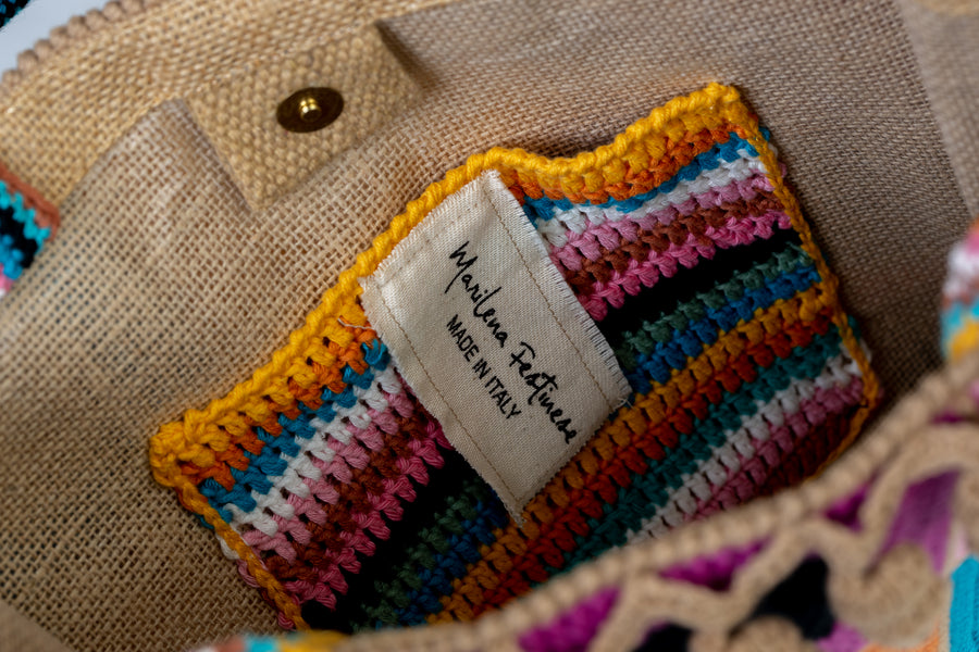 Design patchwork coronato da una splendida e sottile cornice beige, completata da un manico multicolore e dagli “sbaruffi” elicoidali. Tote Bag eccentrica e vivace, realizzata all’uncinetto. La sua tracolla rimovibile permette di portare la borsa a spalla. Di manifattura artigianale, prodotta in Italia.